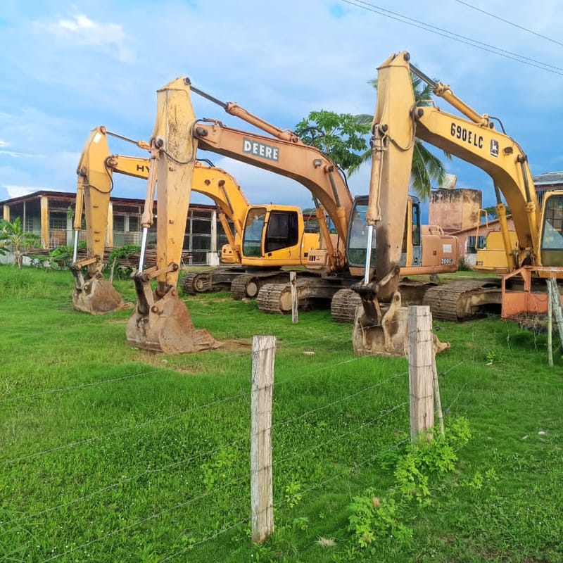 Tres excavadoras hidráulicas alineadas en el patio, entre ellas una John Deere 690 ELC